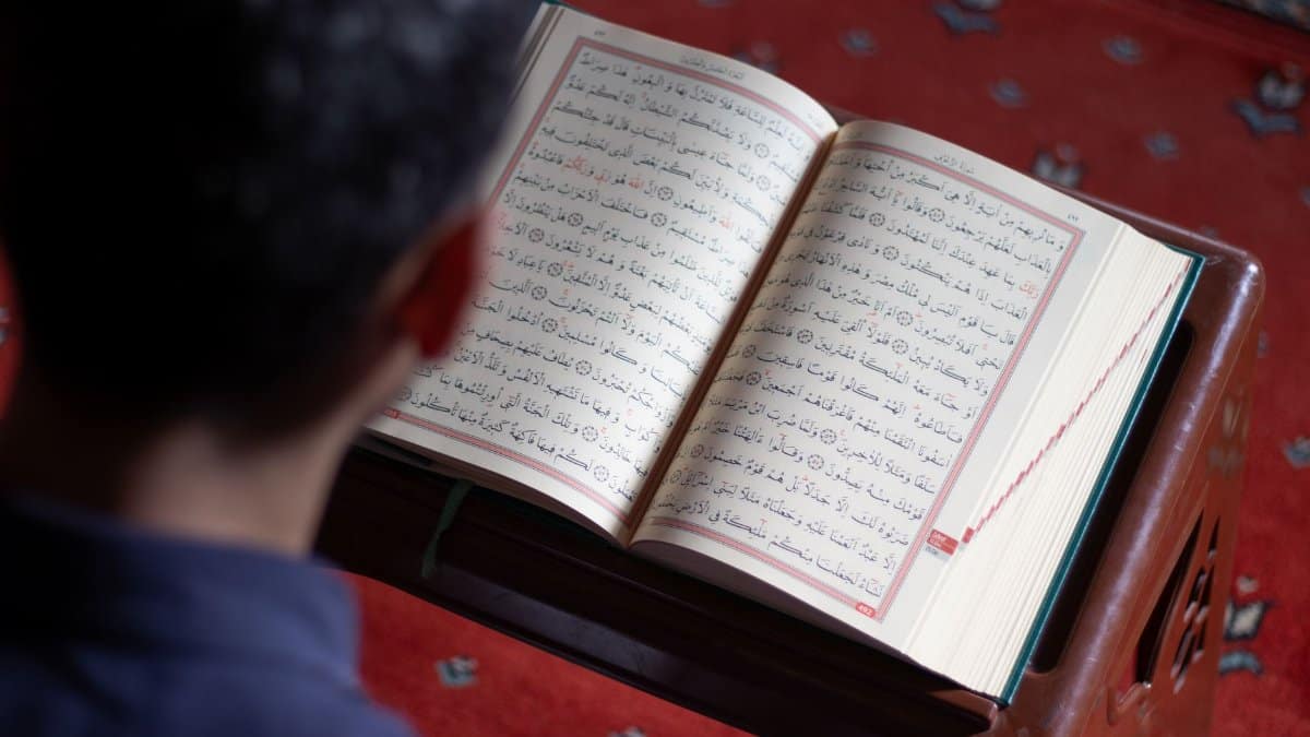 A man reads the Quran, highlighting Islamic faith in a mosque ambiance.