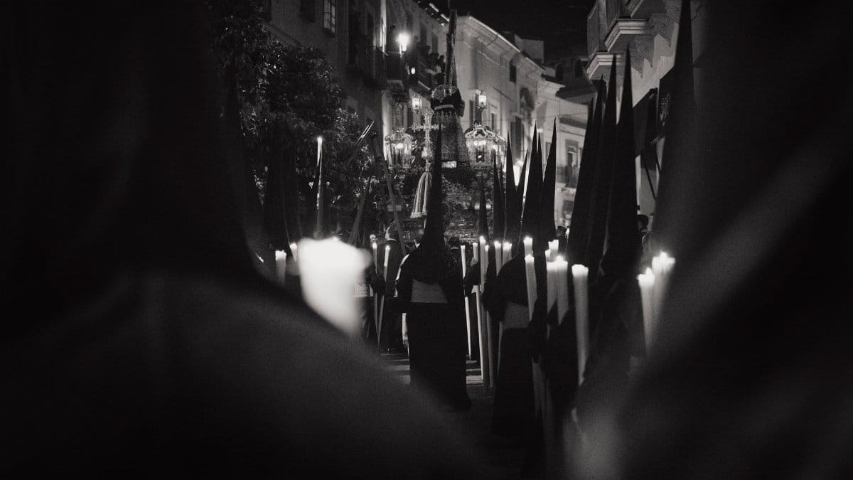 Monochrome photo of a traditional Easter procession at night in Carmona, Spain.