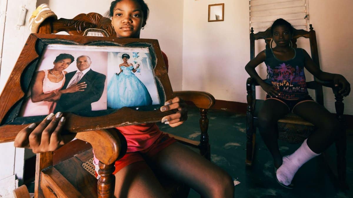 Two girls seated in a room holding a framed family portrait, showcasing heirlooms.
