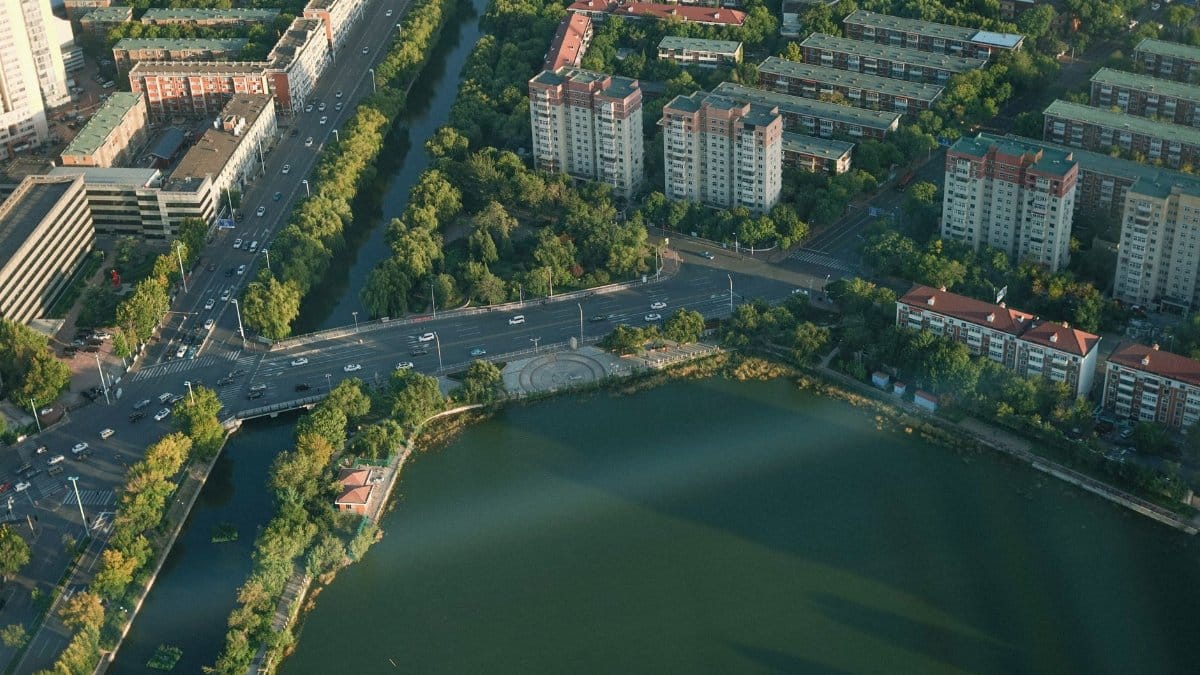 Aerial view of a city with a river, roads, and residential buildings.