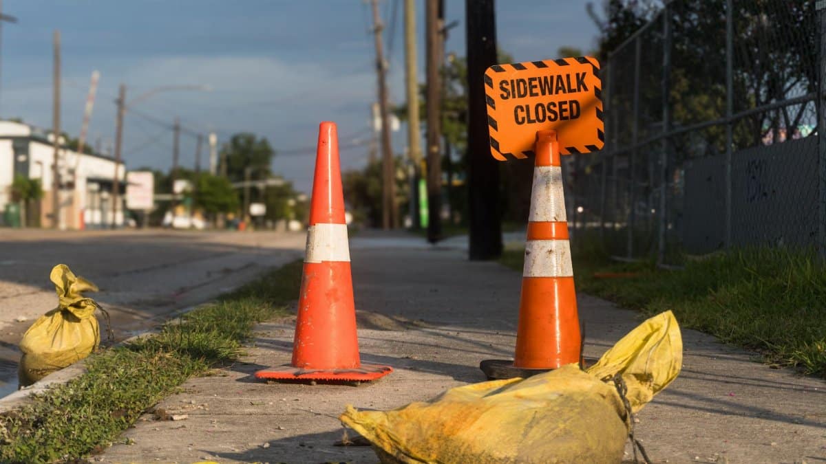 Orange traffic cones and closed sidewalk sign on urban street in Houston.