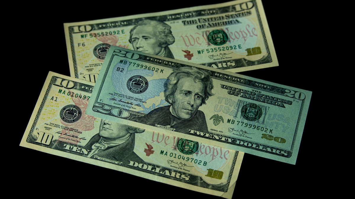 High angle view of US 10 and 20 dollar bills on a black background, emphasizing finance and currency themes.