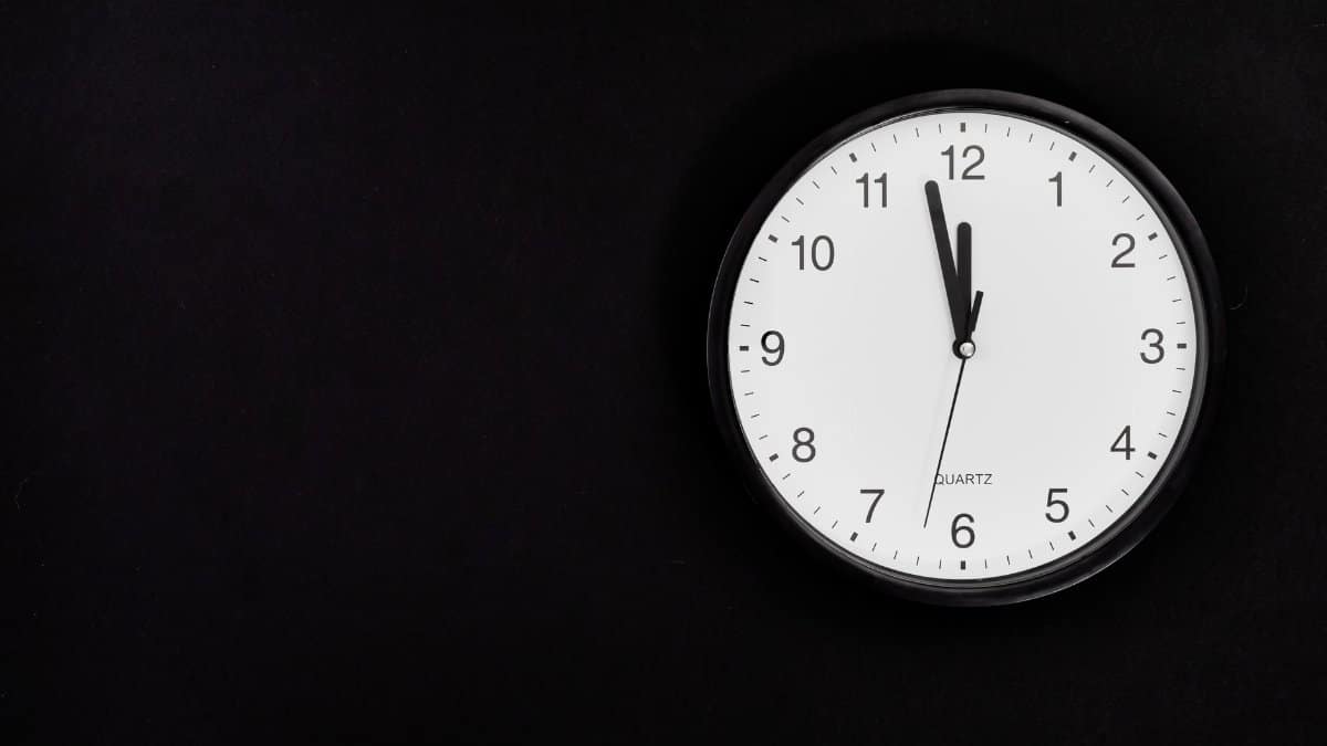 A simple wall clock set at midnight on a black background, ideal for business or time-related concepts.