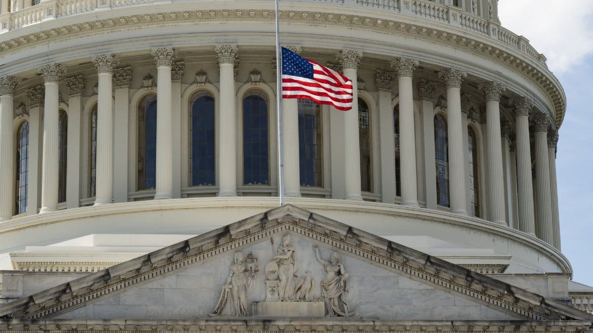 Close-up of the Capitol building in Washington DC with the US flag waving in front.