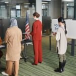 Diverse group of voters lining up at an indoor polling station on election day.