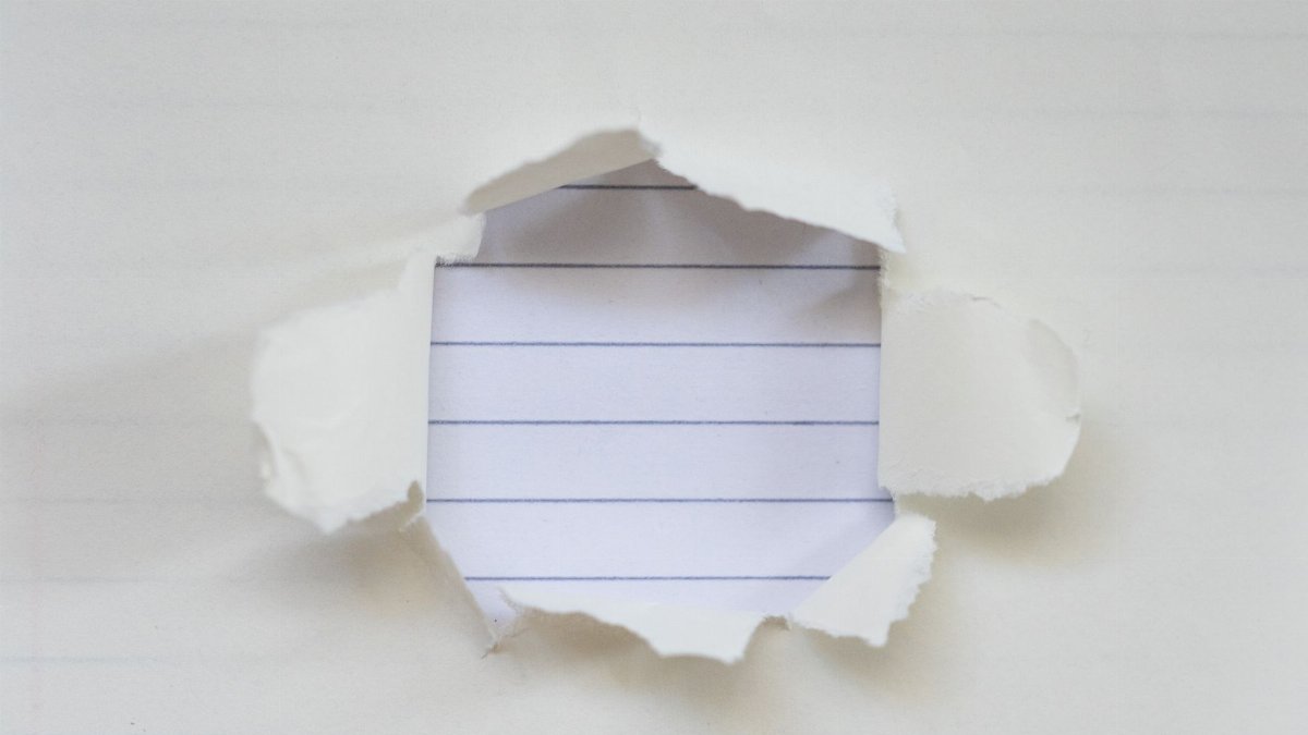 Torn white paper exposing a lined notebook page beneath.