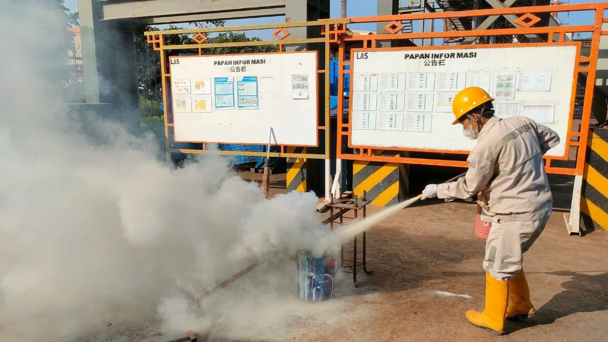 Worker conducts fire safety training outdoors with extinguishers.