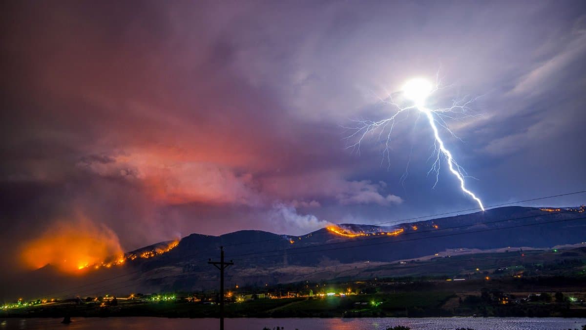 Lightning strikes through a fire-lit sky over Wenatchee, WA, creating a dramatic natural landscape.