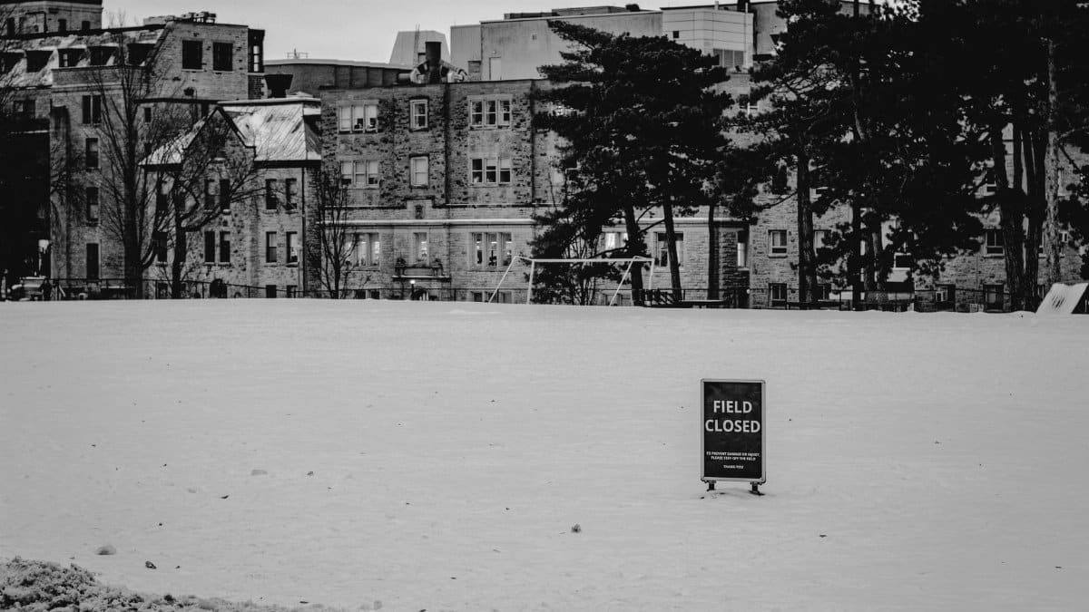 Black and white image of a snow-covered field with a 'FIELD CLOSED' sign in Kingston, Ontario.