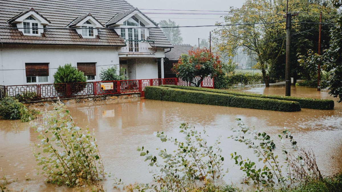 A suburban house surrounded by floodwaters after heavy rain, showing impact of natural disaster.