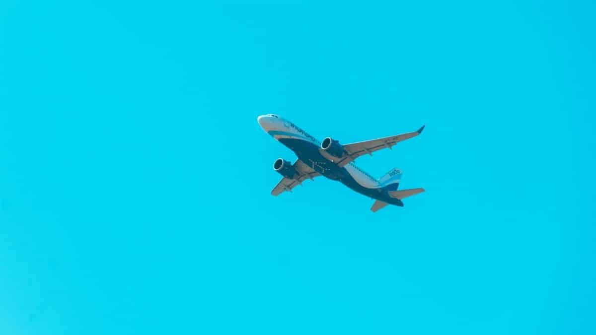 A commercial jet soars through a bright blue sky, showcasing aviation power.
