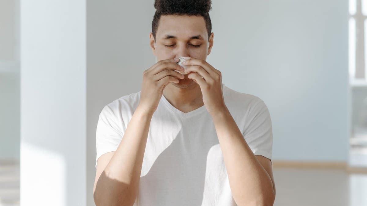 A man sneezing into a tissue, illustrating symptoms of flu or allergies.