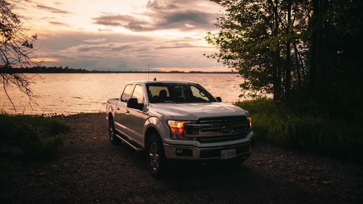 Scenic view of a Ford F-150 truck by a lakeshore in Quebec City at sunset, showcasing the beauty of rural Canada.