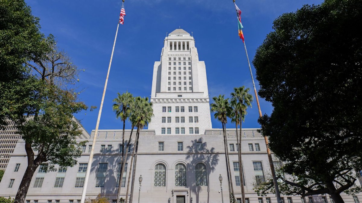 Stunning view of Los Angeles City Hall surrounded by palm trees and clear blue skies.