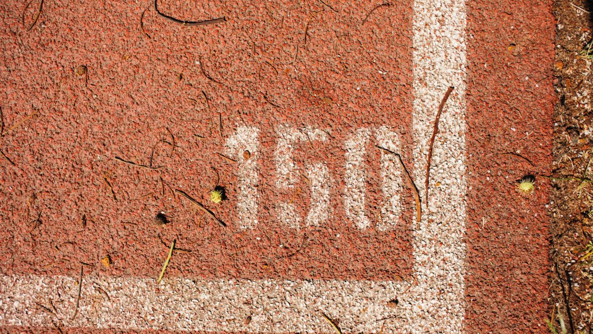 Close-up of a running track showing the number 150 marked on red surface with white lines.