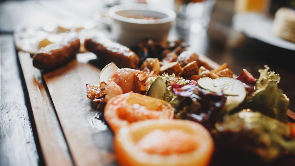 Soft focus of salad made of tomato and cucumber with sausages on wooden dish on table at soft daylight