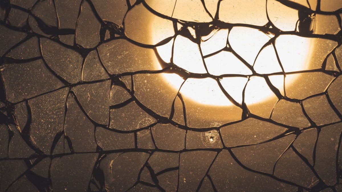 Artistic close-up of a cracked glass pattern illuminated by backlighting, creating a warm and dramatic effect.