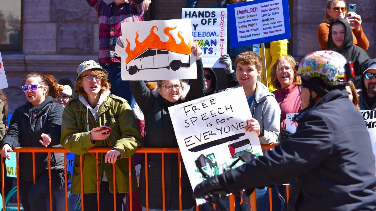 A large group of enthusiastic protesters holding signs advocating free speech and human rights.
