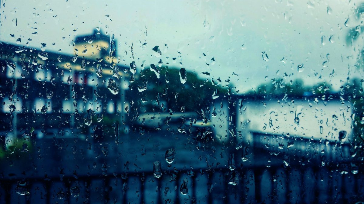 Artistic view through a rain-soaked window capturing blurred cityscape in the background.