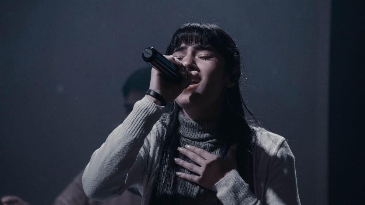 A woman passionately singing into a microphone during a live performance indoors.