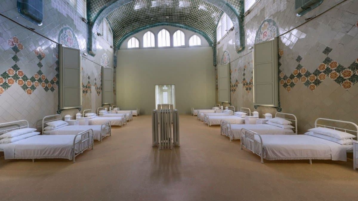 Spacious hospital ward with vintage beds and decorative tiles, offering a glimpse into historical medical architecture.