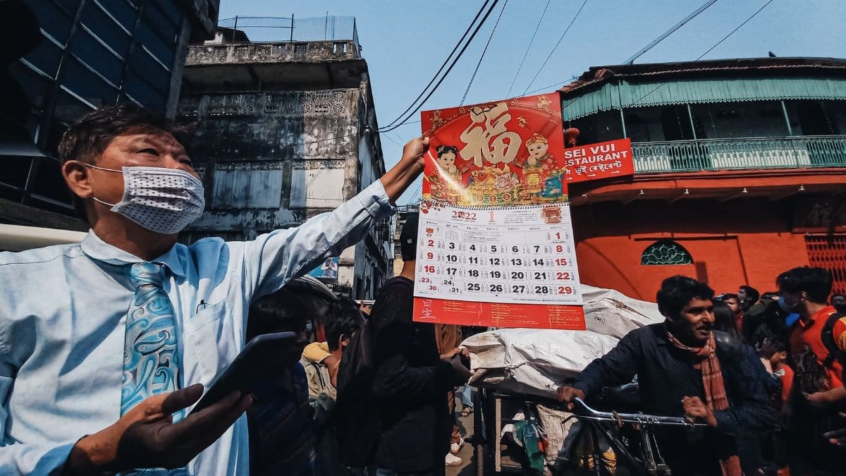A street vendor displays a calendar in a bustling Kolkata market, showcasing diverse culture.