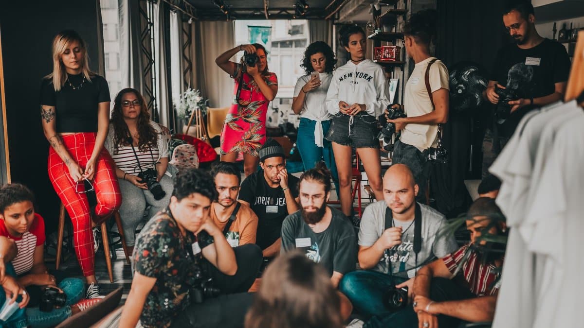 Group of multiracial people wearing casual outfits gathering together in modern studio near female speaker on mat and listening attentively