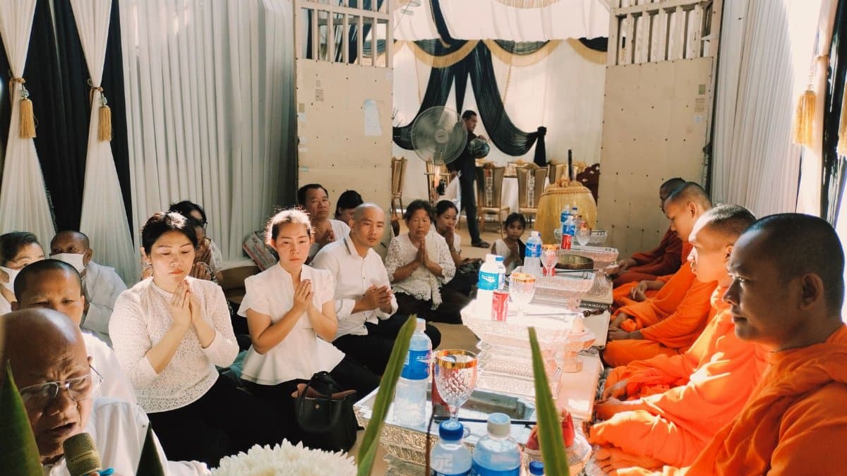 A gathering of monks and individuals in a traditional ceremony, showcasing cultural and religious practices.