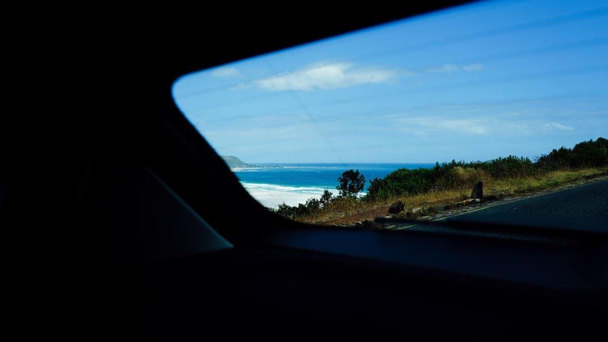 Experience a breathtaking coastal view captured through a car window on a bright, sunny day.