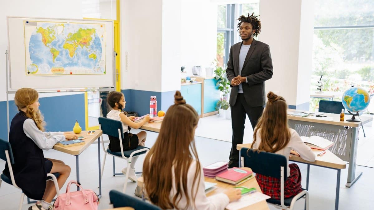 Teacher engaging with students in a bright, modern classroom setting.