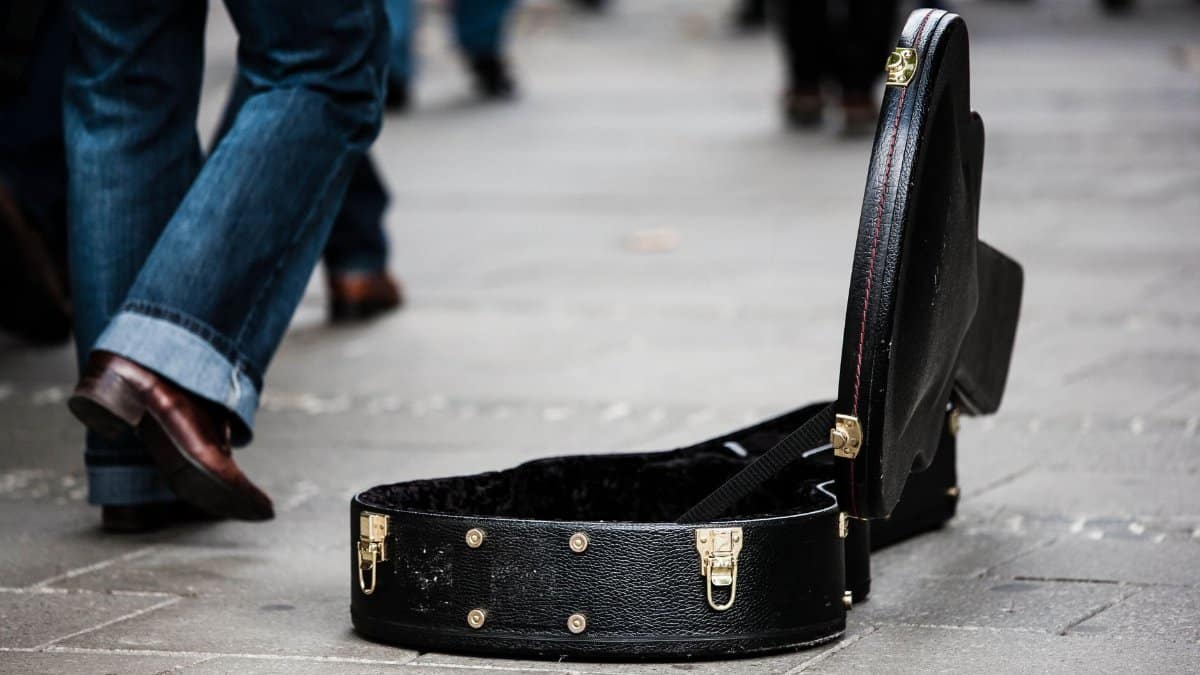 An open guitar case on a busy street, symbolizing live street performances.
