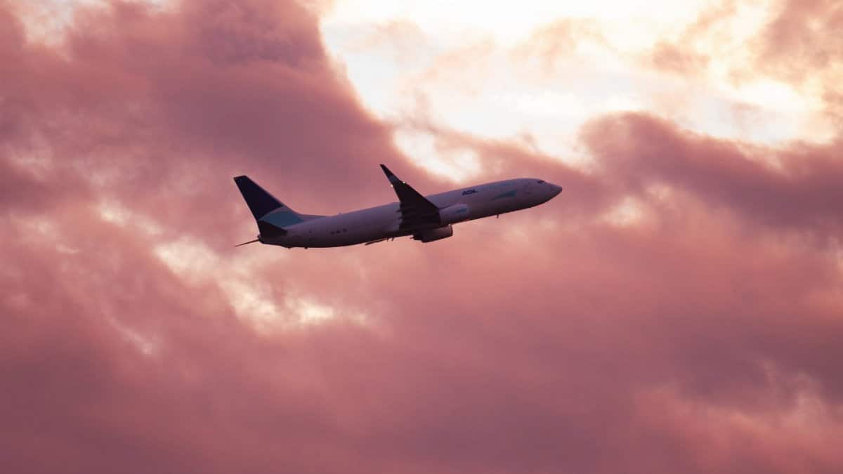 Airplane silhouetted against a dramatic pink sunset sky in Gothenburg, Sweden.