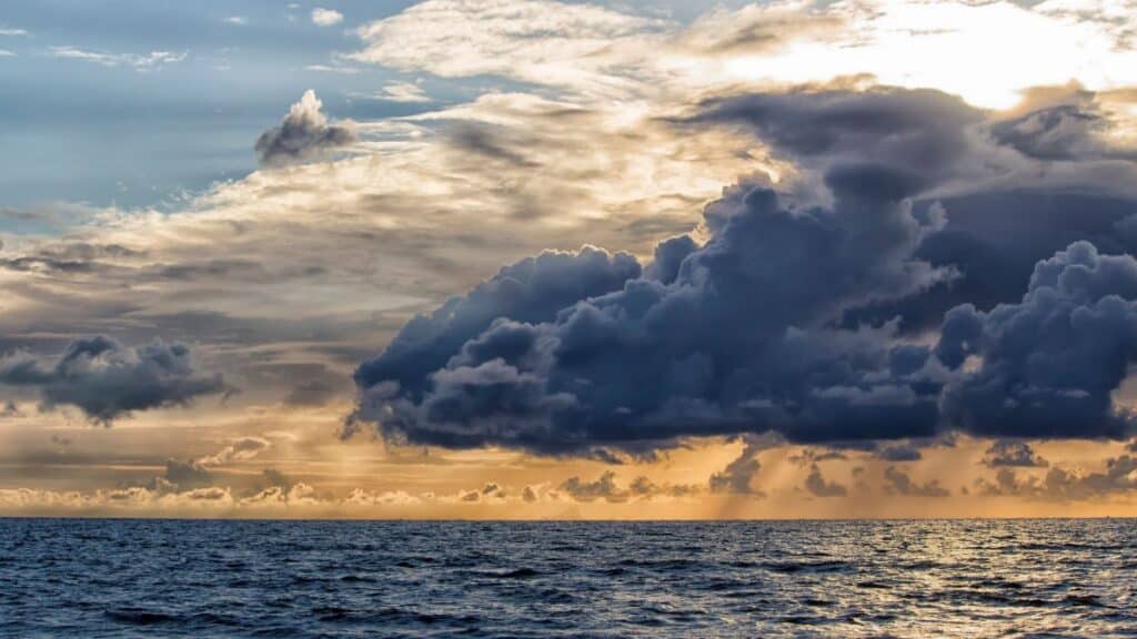 Stunning photo of a dramatic seascape with a vibrant sunset and impressive cloud formations.