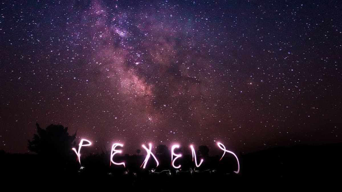 Long exposure shot capturing a starry night sky with creative light writing in the foreground.