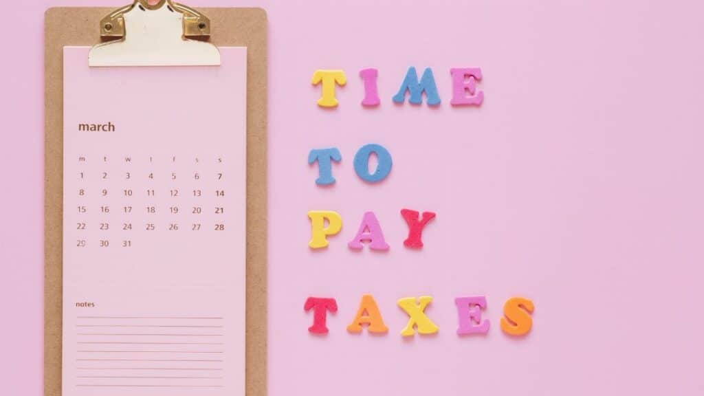 Colorful tax reminder on clipboard against a pink background for March
