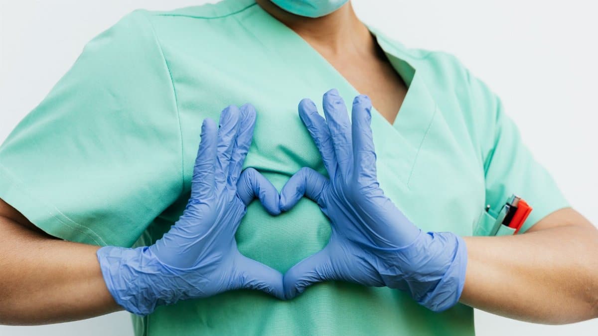 Medical professional forming a heart shape with blue gloves. Symbol of care and compassion.