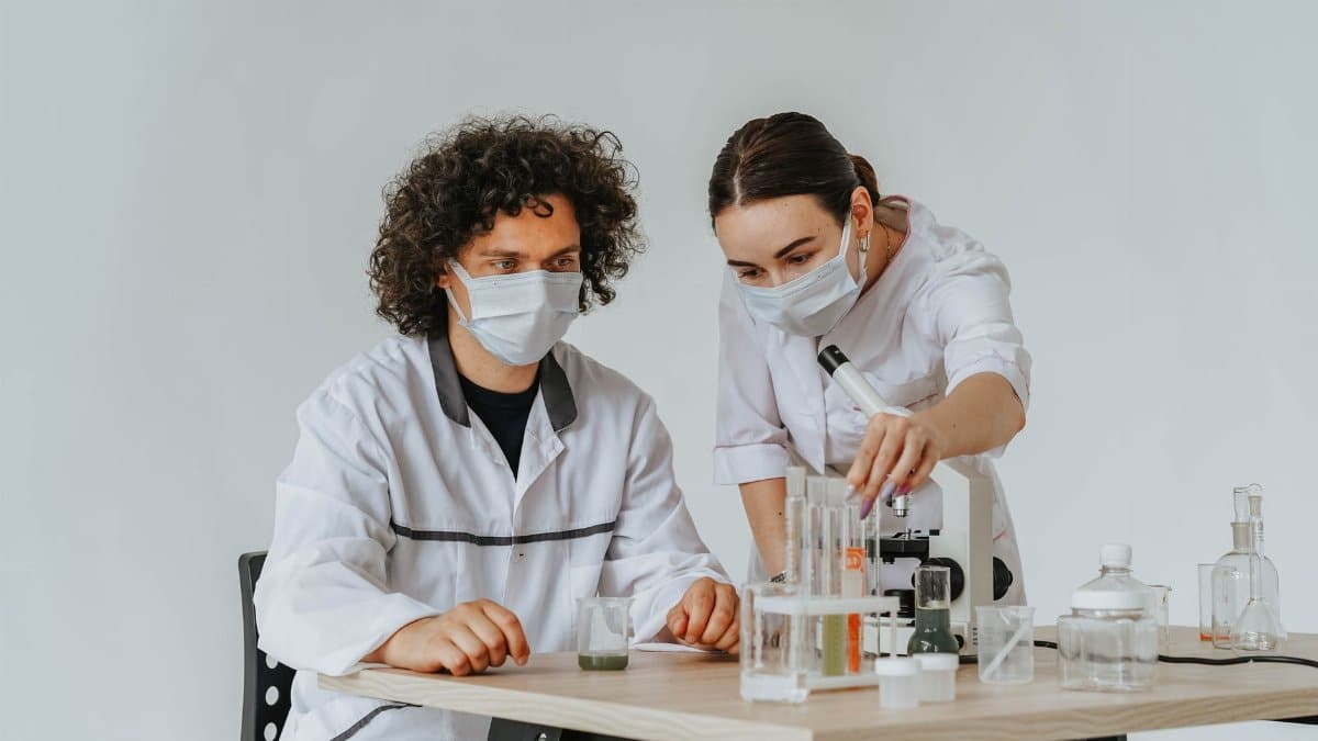Two scientists working on experiments in a laboratory with microscopes and test tubes.