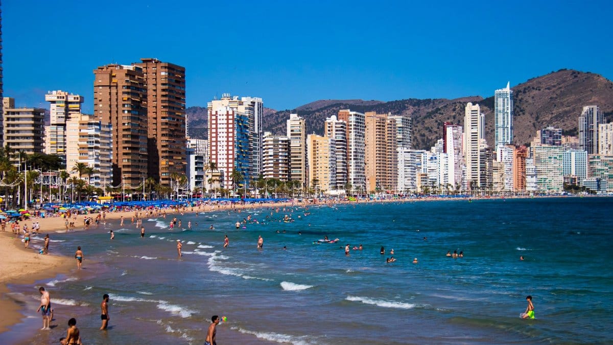 Beautiful beach scene with high-rise buildings in Benidorm, Spain under a clear blue sky.