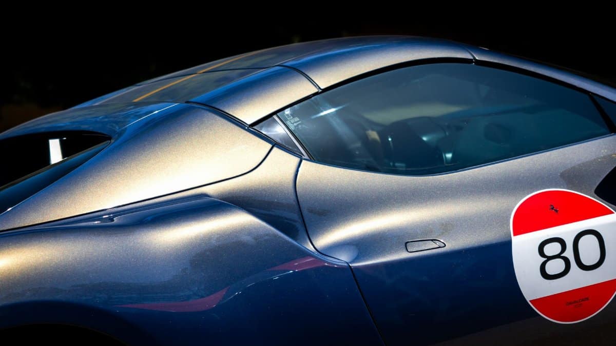 Detailed shot of a sleek metallic sports car with number decal, showcasing luxury and performance.