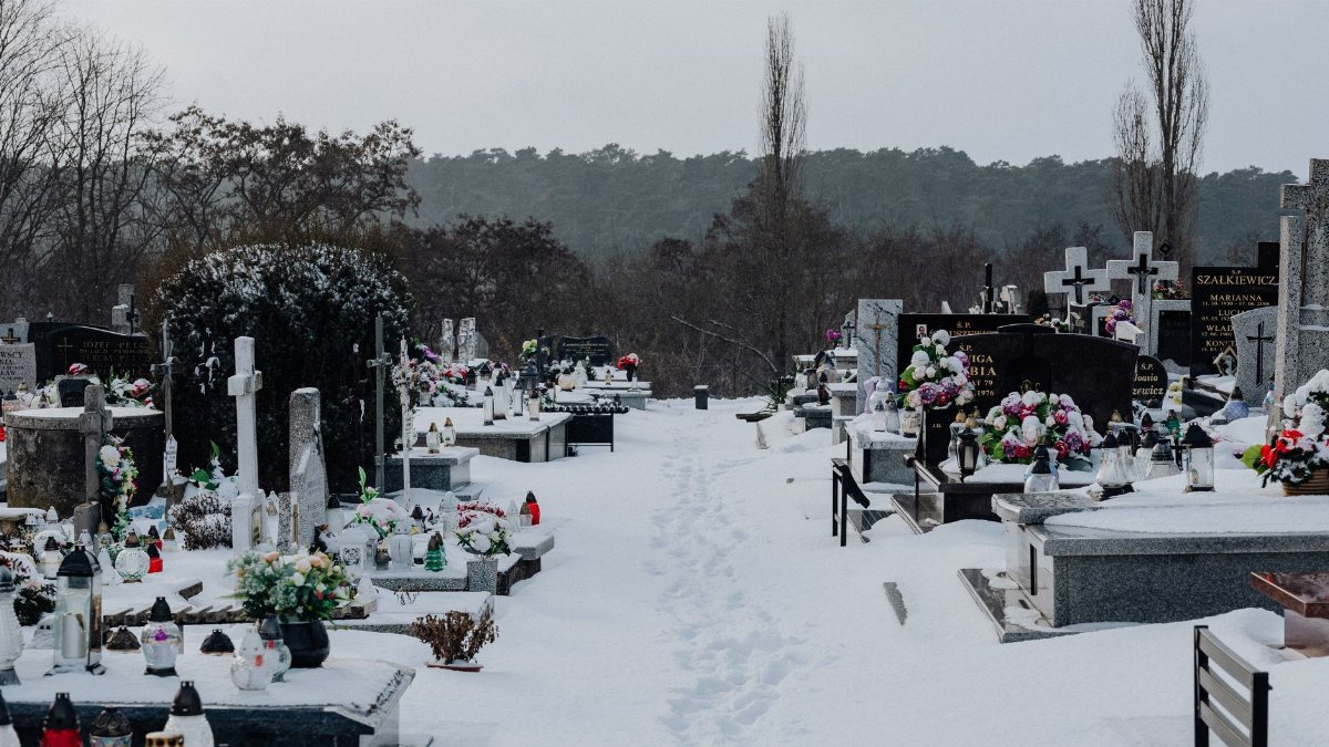 Quiet winter cemetery landscape with snow-covered graves and tombstones.