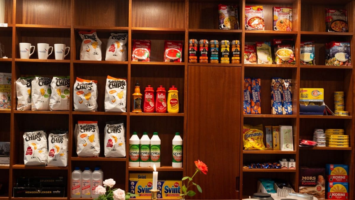 Wide array of packaged groceries neatly arranged on wooden shelves in a store setting.