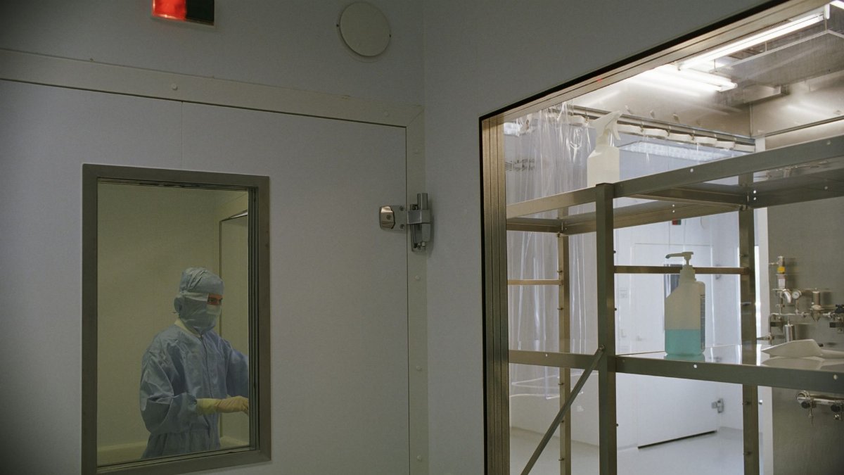 Image of a cleanroom in a medical facility featuring sterile equipment and a person in protective clothing.