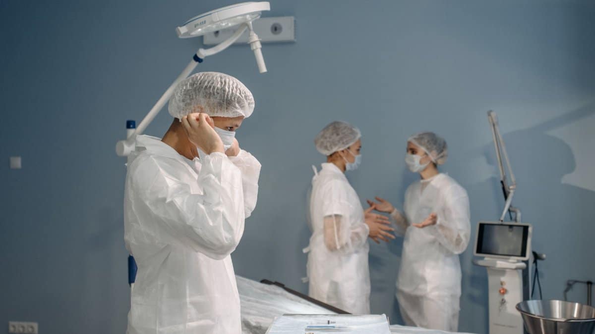 Doctors in PPE preparing for surgery in a clinical setting.