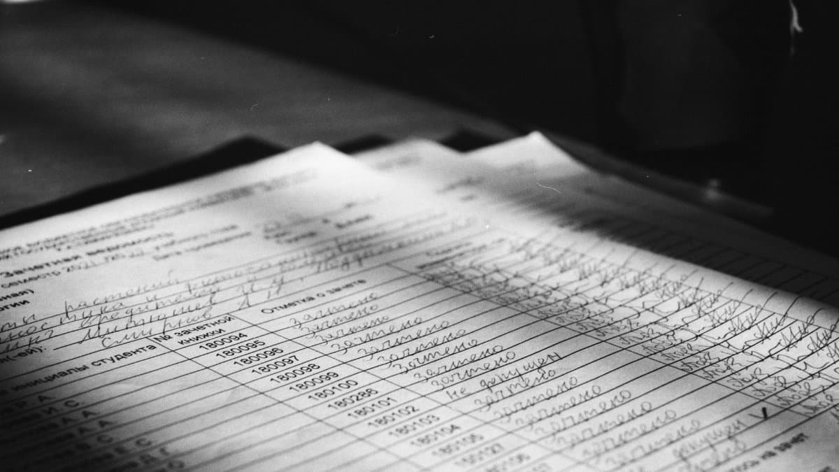 Close-up grayscale photo of a handwritten document with visible text and shadows.