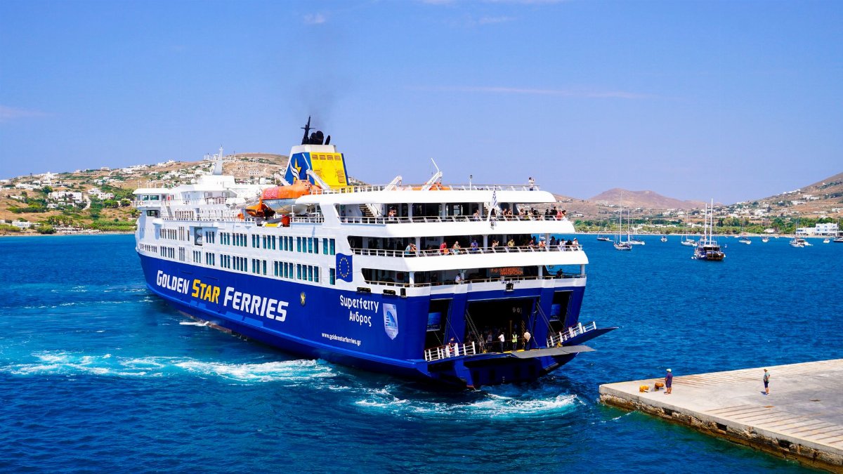 A vibrant image of a Golden Star ferry approaching a Greek island pier under a clear blue sky.