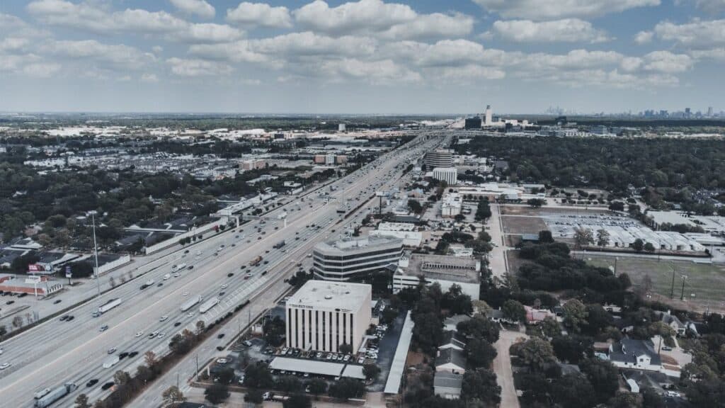 Expansive aerial cityscape with highway, showcasing urban development and open sky.