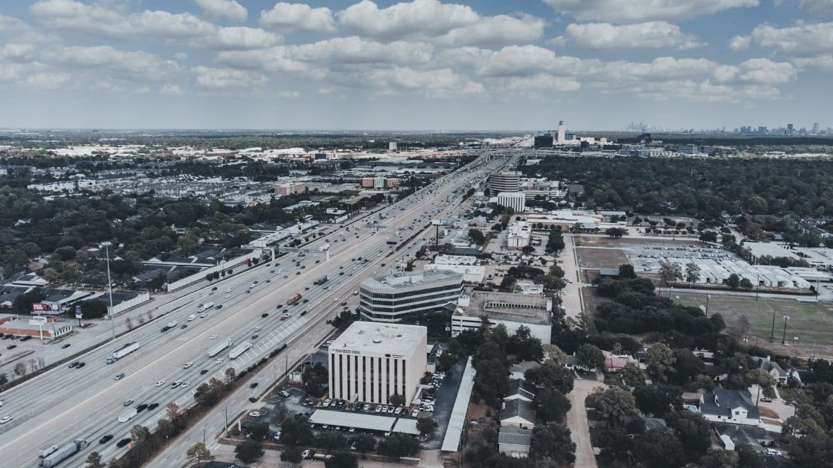 Expansive aerial cityscape with highway, showcasing urban development and open sky.