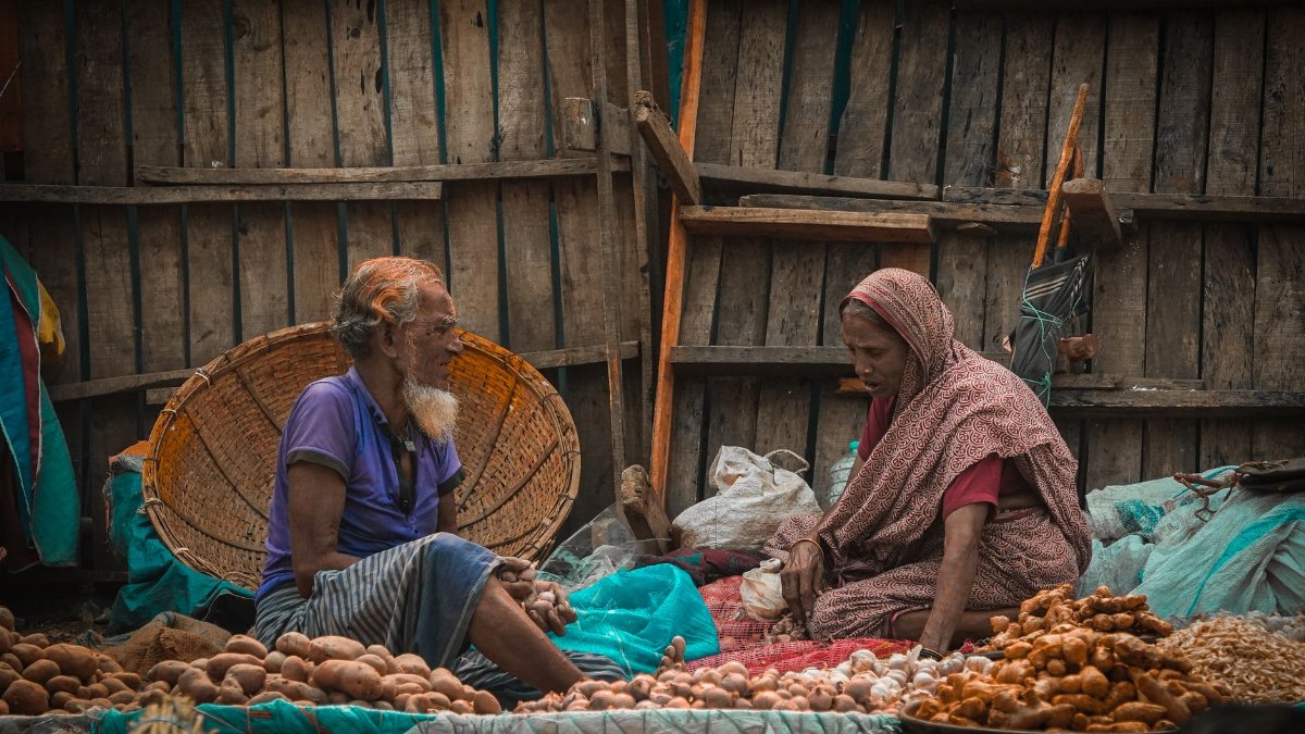 Two vendors at a market in Dhaka, Bangladesh, selling fresh produce.