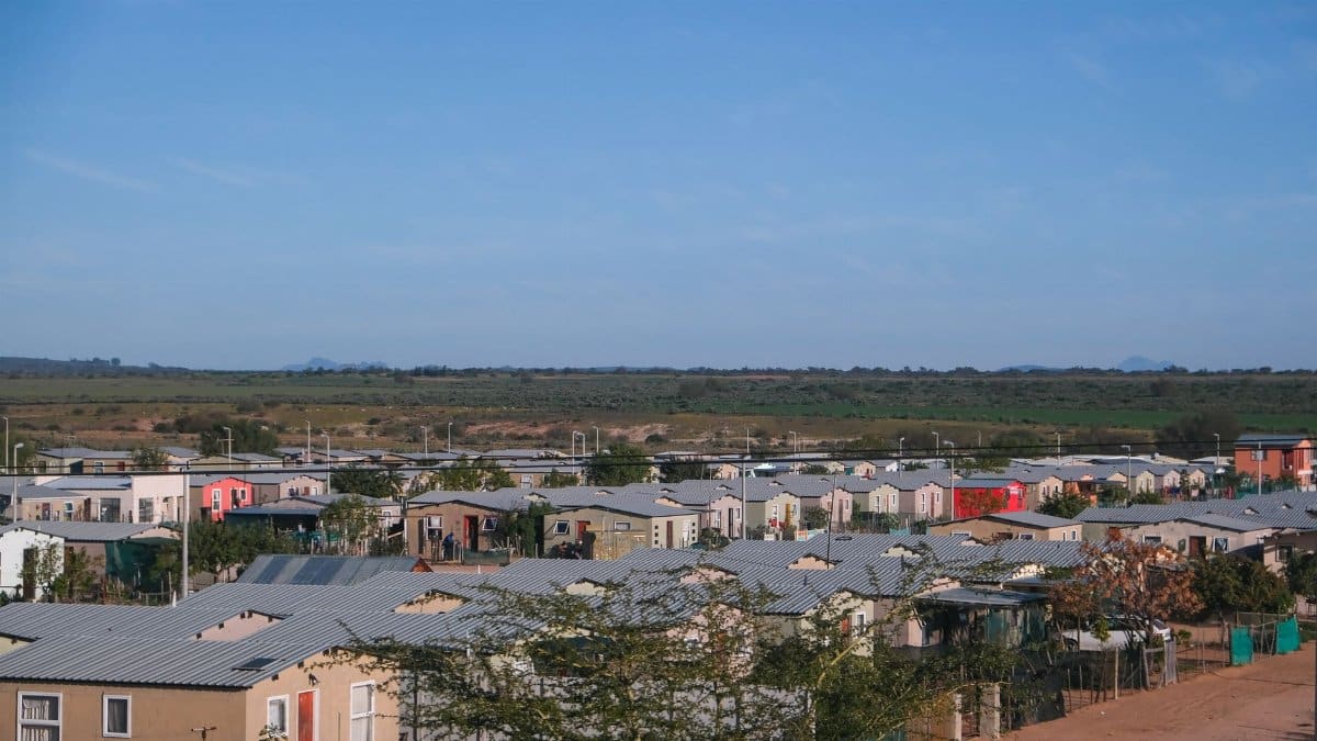 Drone shot of a small residential neighborhood with concrete houses on a clear day.