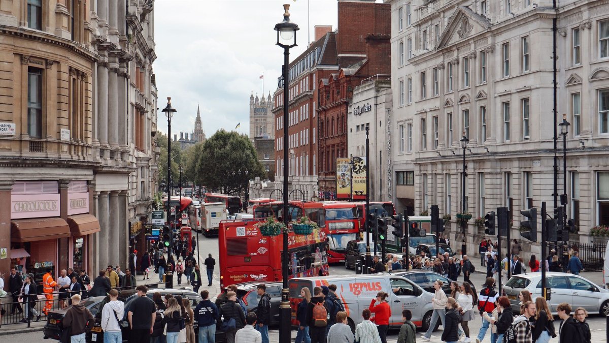 A bustling London street filled with people and iconic red buses, showcasing urban life in the city.